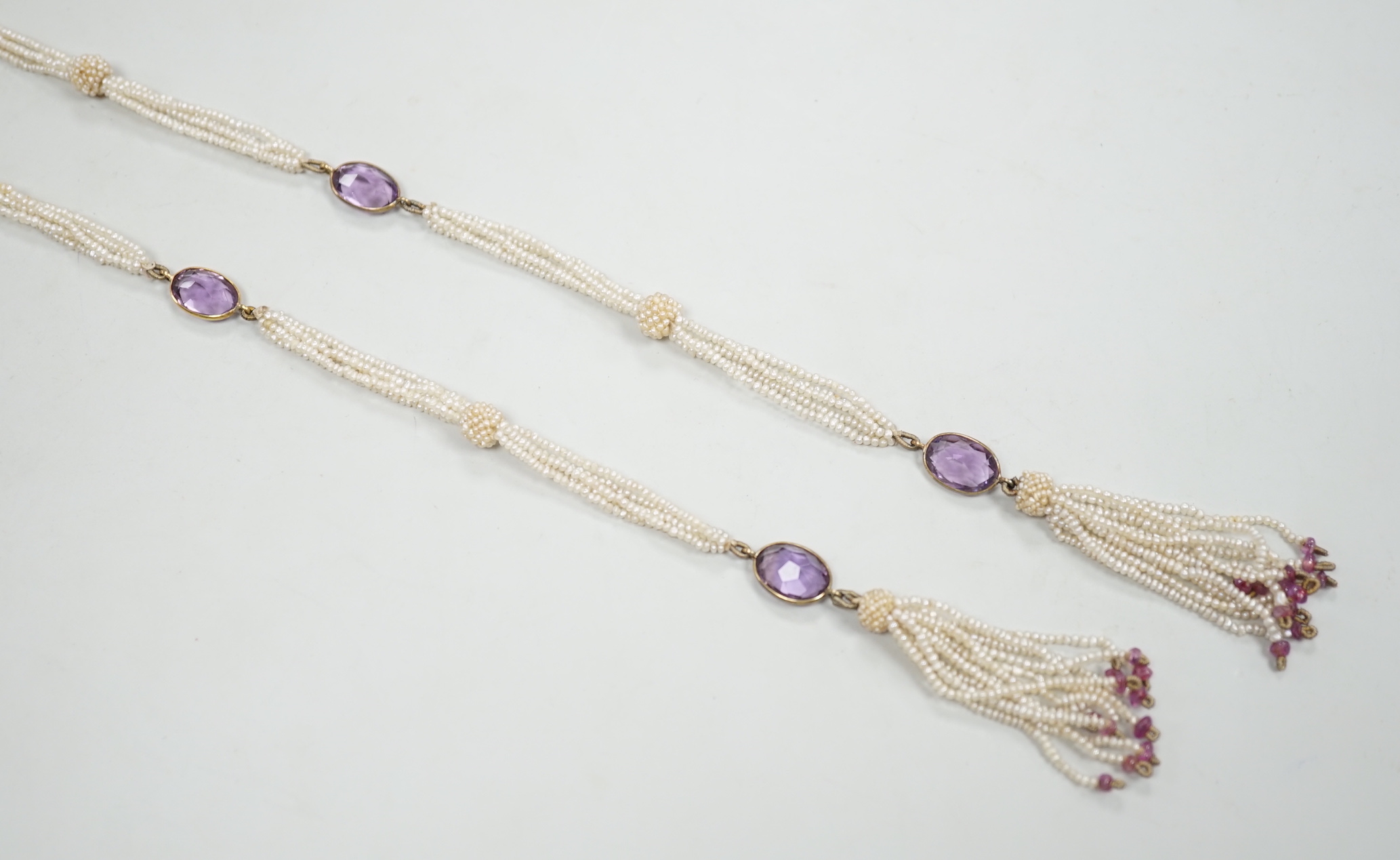 A 19th century Indian multi strand seed pearl and oval cut amethyst set long necklace, with gem set tassel drops, 166cm.